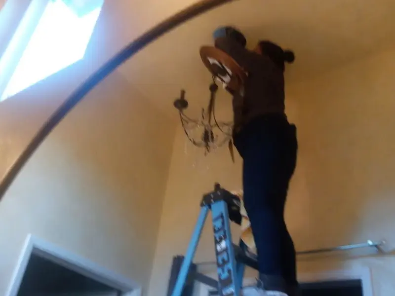 Electrician installing a chandelier in a Baker residence